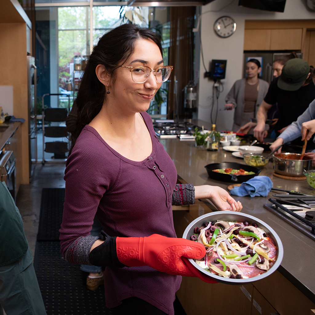A woman holds a bowl of salad that she prepared in Charlee's Kitchen as part of the Food as Medicine Everyday series of nutrition-focused cooking classes presented by National University of Natural Medicine's Food as Medicine Institute.